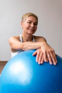 senior-woman-with-short-hair-using-fitness-ball_23-2148827685