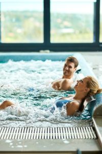 happy-woman-her-husband-enjoying-water-massage-thermal-pool-health-spa-copy-space_637285-7512